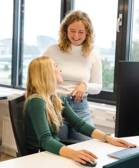Corporate recruiter en employer branding adviseur lachend op de foto achter de computer.