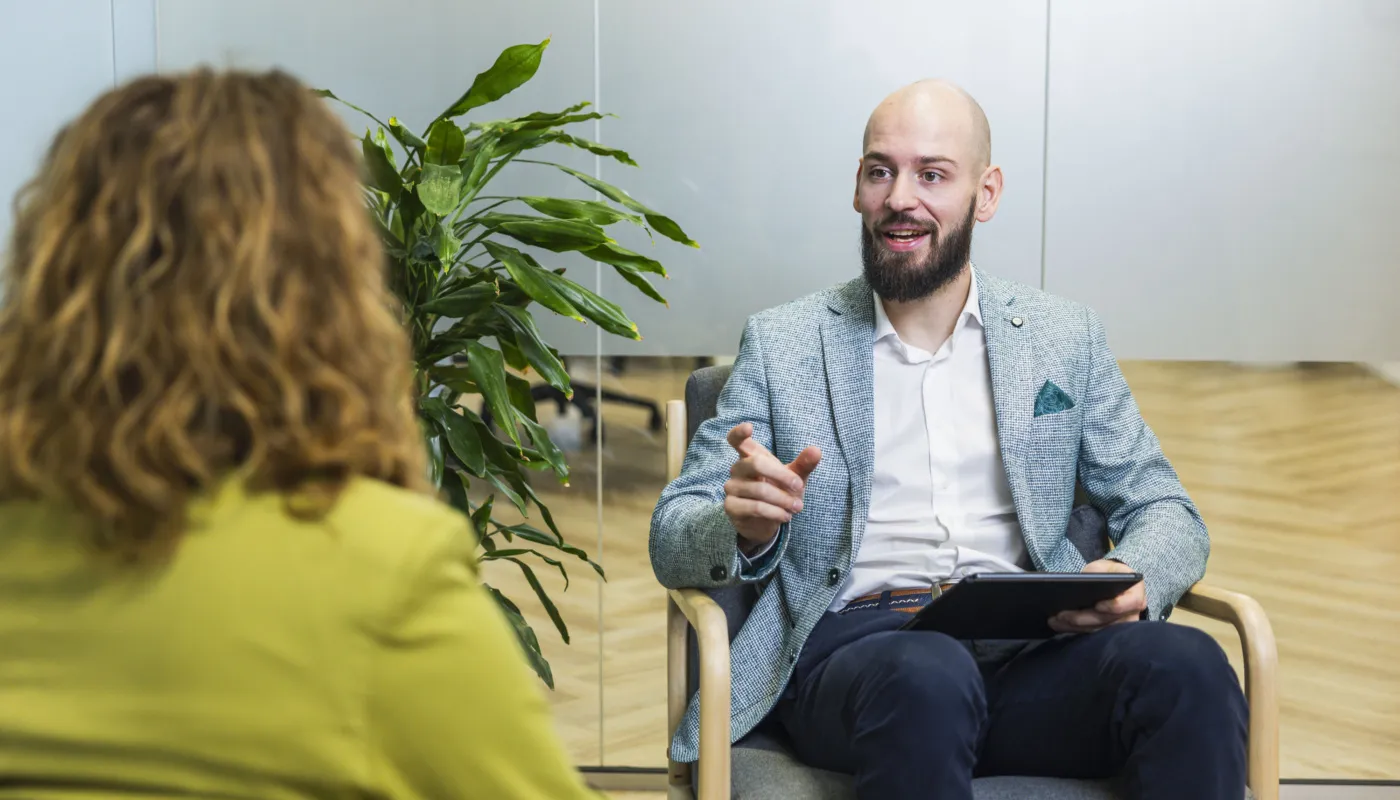 Employer branding adviseur zittend in stoel, in gesprek met collega.