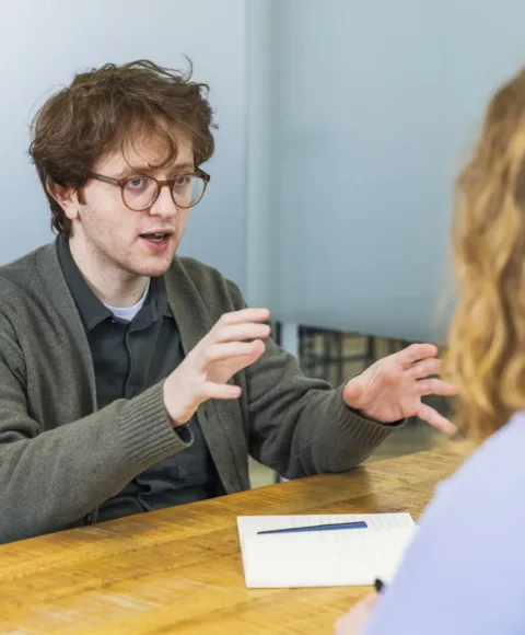 Meeting tussen 2 marketing collega's, man scherp in beeld, vrouw op voorgrond niet in focus.